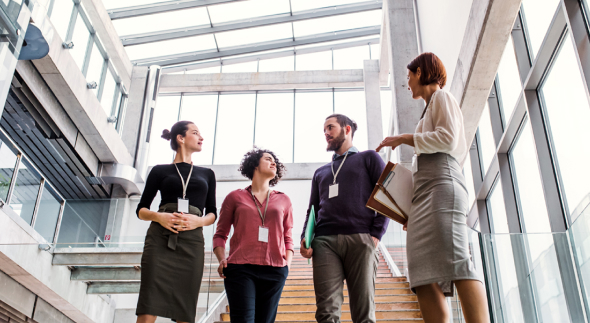 Group of coworkers convening in a common area in the office and talking