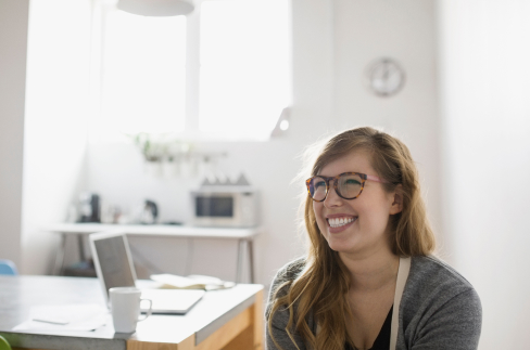 Young person sitting in an apartment smiling at something off camera